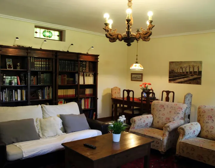 Interior · salón con biblioteca, sofá y sillones.