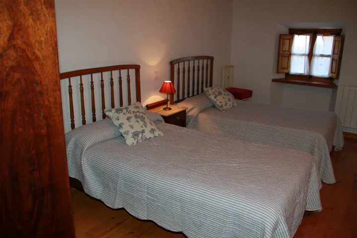 Interior · dormitorio de dos camas junto a la ventana.